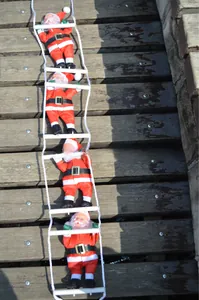 Detail of four Santa Claus figures climbing a white rope ladder for Christmas decor