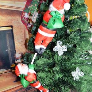 Père Noël grimpant sur corde décorations de sapin de Noël avec costumes rouges et sacs