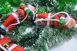 Close-up of three Santa Claus dolls on a white rope with festive tinsel backdrop