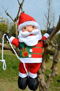 Close-up of Santa Claus hanging decoration with climbing rope on a tree trunk