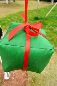 Detail of red and green festive gift box hanging ornament with ribbon and satin handle