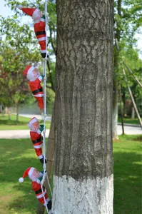 Detail view of four Santa Claus figurines climbing a white rope ladder for outdoor decoration