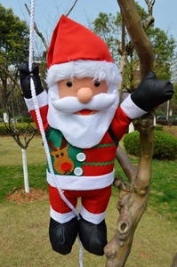 Detail of Christmas Santa climbing rope decoration hanging on a tree trunk in park