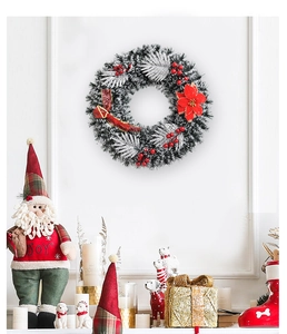 Detailed Christmas wreath with red berries, poinsettia and snow-flocked needles on wall