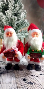 Close-up of two Santa dolls with Merry Christmas signs and mini gift boxes for decor