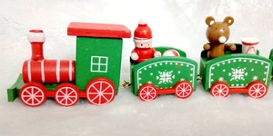 Close-up of wooden Christmas train featuring a Santa figure and bear on white plush snow