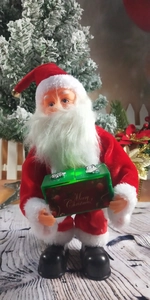Close-up of a Christmas Santa doll holding a green Merry Christmas gift box decor