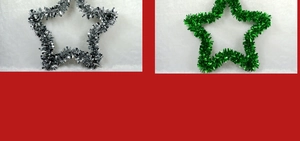 Detail of silver and green star-shaped Christmas tinsel garlands on white plush background