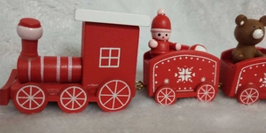 Close-up of wooden Christmas train toy with snowman and bear figures on snowy background