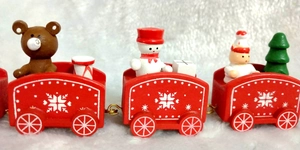 Detail of wooden Christmas train carriages with mini snowmen and festive bears on white faux fur