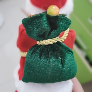 Detail of Santa Claus wearing a green velvet gift bag with gold cord and bead detail
