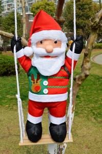 Detail of Christmas Santa hanging on wooden swing with reindeer vest in garden tree