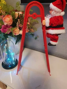 Gros plan du Père Noël électrique grimpant sur une échelle rouge pour décoration festive