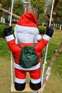 Outdoor view of Santa Claus hanging on a rope ladder with a green gift bag detail
