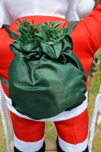 Detail of Christmas Santa doll wearing red velvet suit with a green satin gift bag