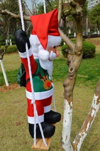 Detail of Santa Claus ornament hanging on a wooden swing with green reindeer vest