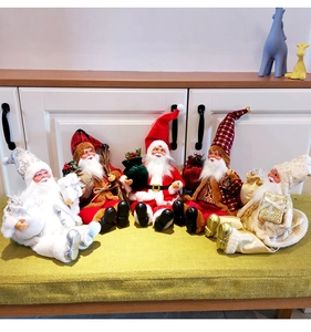 Group of five sitting Santa Claus plush dolls in assorted colors on a green bench