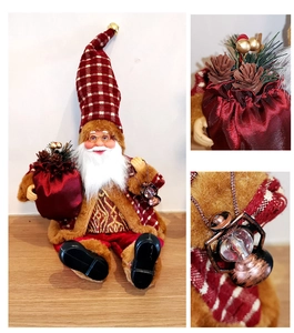 Detail of sitting Santa doll featuring plaid hat with bell, gift bag, and lantern