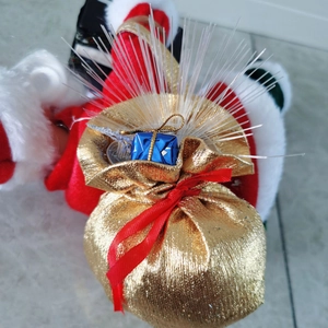 Close-up of golden Christmas gift bag with red ribbon, blue gift box, and fiber optic lights