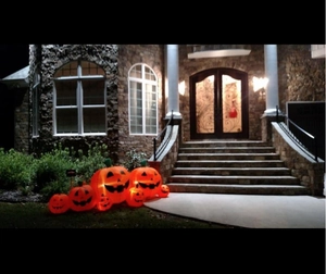 Detail of five glowing inflatable Halloween pumpkins with warm LED lights on garden steps