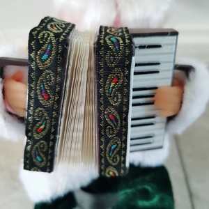 Detail of Santa figurine holding a miniature accordion with festive paisley patterned straps