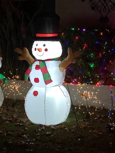 Inflatable Christmas snowman with LED lights and branch arms glowing in a night garden