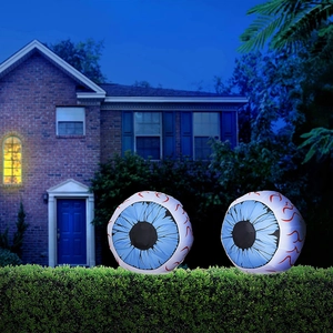 Two Halloween inflatable glowing eyeballs with blue iris and red veins on a garden hedge