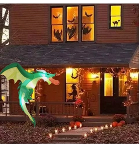 Detail of inflatable green Halloween dragon with yellow wings and fire breath outdoors
