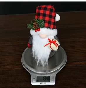 Detail showing a Christmas gnome with red plaid hat holding a gift box on a scale
