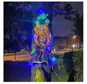 Detail of hanging Halloween tree witch with orange hair, striped skirt and colorful LED lights