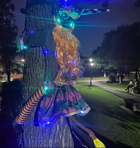 Halloween tree-crashing witch with colorful LED lights, orange hair and striped socks