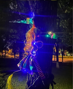 Detail of Halloween tree-climbing witch with colorful LED lights and orange curly hair