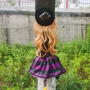 Detail of hanging Halloween witch decor with purple striped skirt and broom on tree trunk