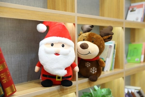Detail of plush Christmas Santa and reindeer toys with snowflake embroidery on wooden shelf
