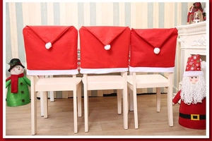 Three red Christmas hat chair covers with white pom-poms for festive dining room decor