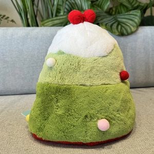 Detail of plush reversible Christmas tree hat with colorful pom-poms on a grey sofa
