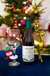 Gros plan d'un verre à vin de Noël avec pendentif bonhomme de neige et décor de renne