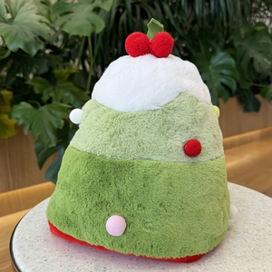 Green plush Christmas tree hat with colorful pom-poms and red topper on white surface