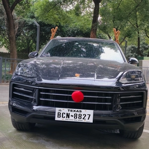 Close-up of plush brown reindeer antlers with bells and red nose on a black SUV car