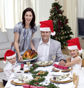 Family wearing red knitted Christmas hats during a festive dinner with roasted turkey