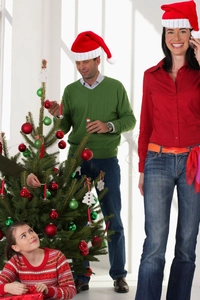 Close-up of festive red and green knitted Christmas hats with holiday tree decorations