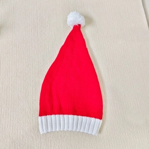 Classic red knitted Christmas hat with white pom-pom and ribbed cuff on beige background