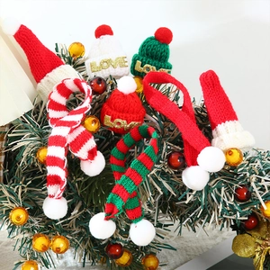 Close-up of mini knitted Christmas hats with LOVE sequins and pom-poms on tree