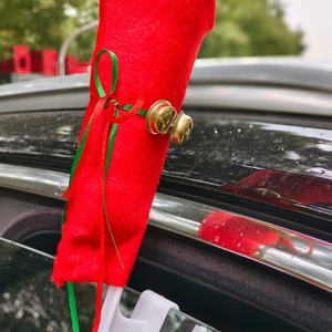 Red Christmas car reindeer antlers with green ribbons and bells on a black vehicle
