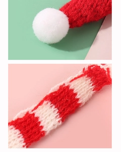 Close-up of knit Christmas mini hat showing soft white pompom and red wool texture