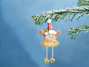 Detail of yellow fabric Christmas gnome with striped hat and bells on pine branch