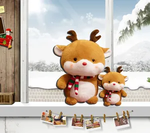 Set of two Christmas reindeer plush toys with striped scarves in a snowy window setting