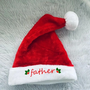 Red plush Christmas hat with white pompom and father embroidery on festive grey background