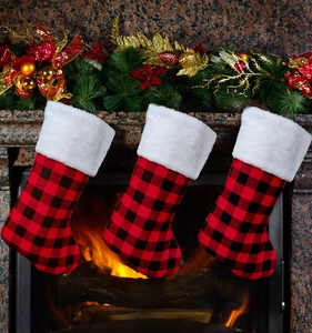 Trois chaussettes de Noël à carreaux rouges et noirs suspendues à un manteau de cheminée
