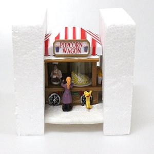 Dettaglio decoro natalizio carretto di popcorn con luci e scena di neve musicale